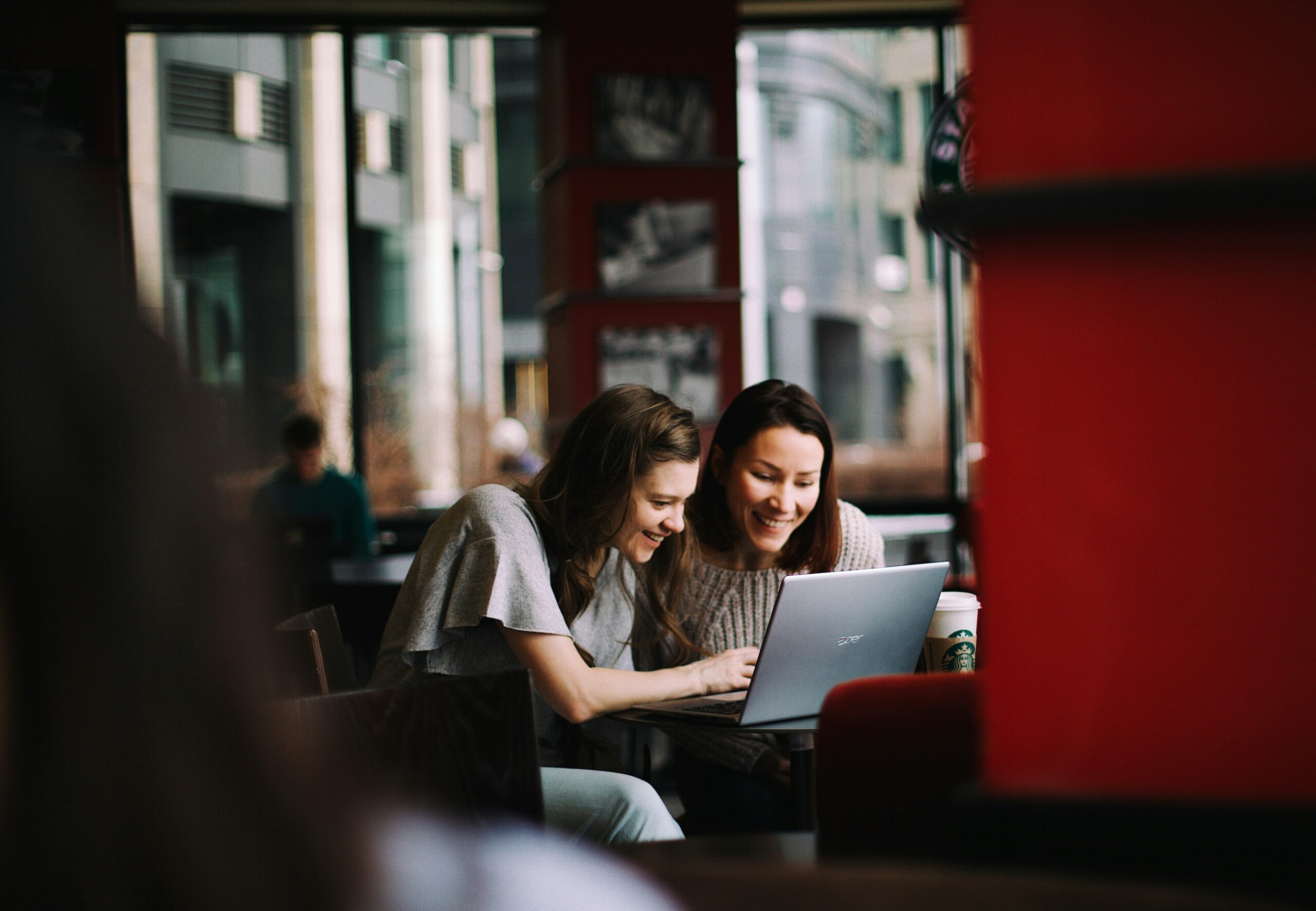 photo of two woman in a mentorship talking and looking at a laptop