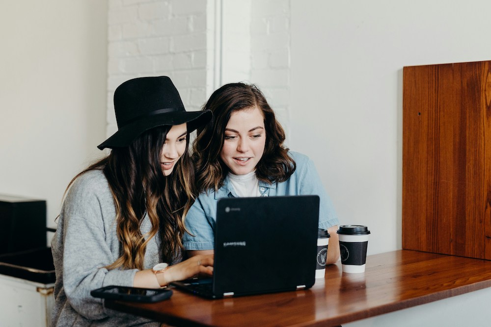 image of two woman freelancers working at coffee shop showing flexibility and not chasing corporate ladder