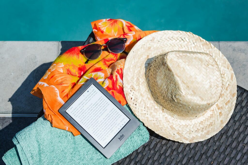 Straw hat, sunglasses, an e-reader, and a colorful beach towel beside a pool—capturing the relaxed, intentional energy of a summer work-life rhythm.
This supports the blog post’s message that your system can shift with the season—blending focus, rest, and joy.