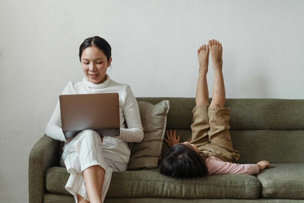Working mom on her laptop with child next to her.