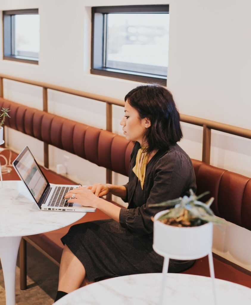 Woman working on a laptop at a coworking space with community and focus.