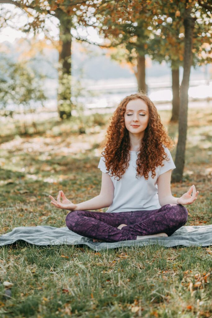 Woman meditating outdoors in a park, symbolizing calm and personal grounding
