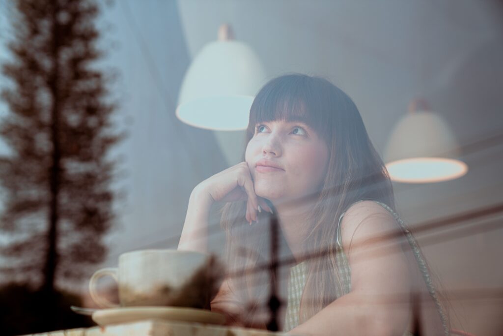 Woman looking out of a window reflecting on life.