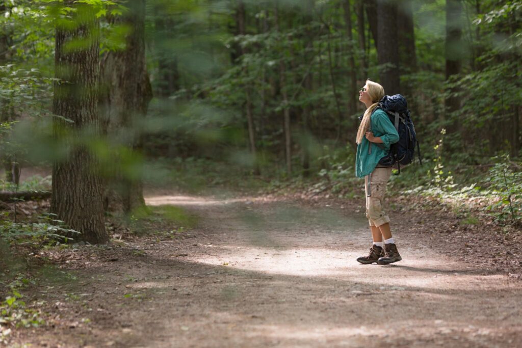Woman walking alone on a sunlit desert trail.