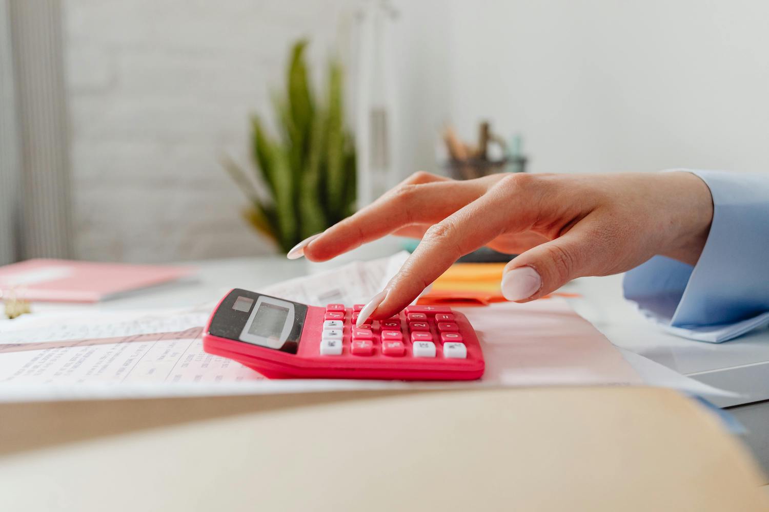 Close-up of a professional managing bookkeeping tasks with a pink calculator, highlighting organization and financial management.